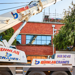 Quinlan Cranes Working On Brick Building
