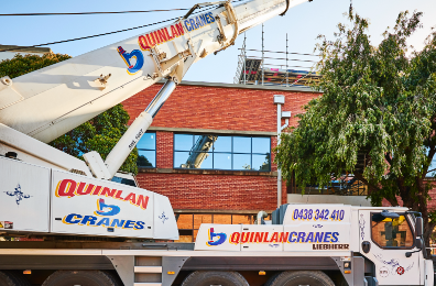Quinlan Cranes Working On Brick Building