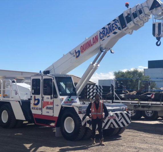 Smiling Trades-person Standing In Front Of Quinlan Rental Crane